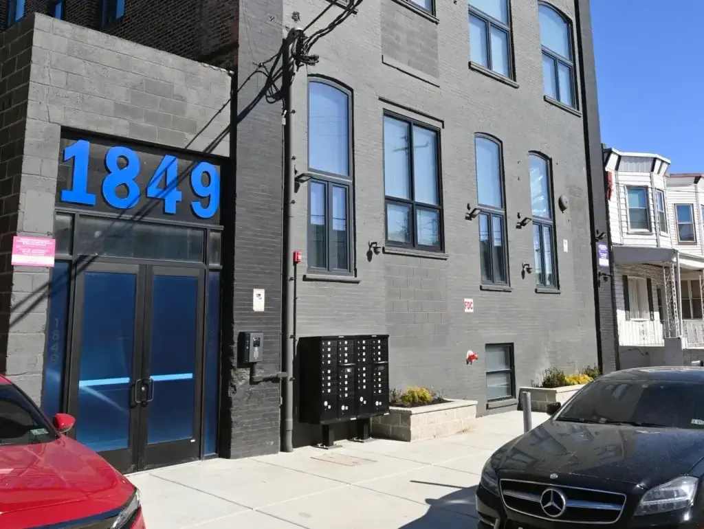 1849 E Venango St also called the Chocolate Factory lofts front view of the loft apartments featuring black brick with blue street letters